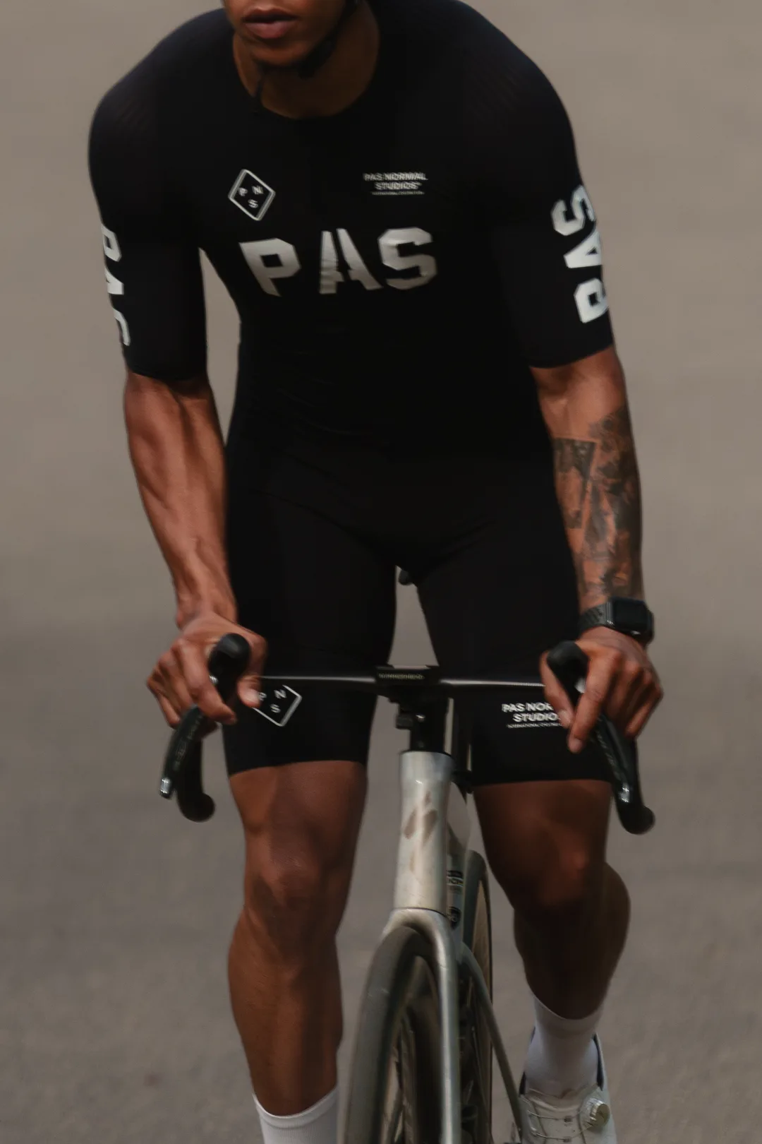 Cyclist on the drops in a black PAS kit