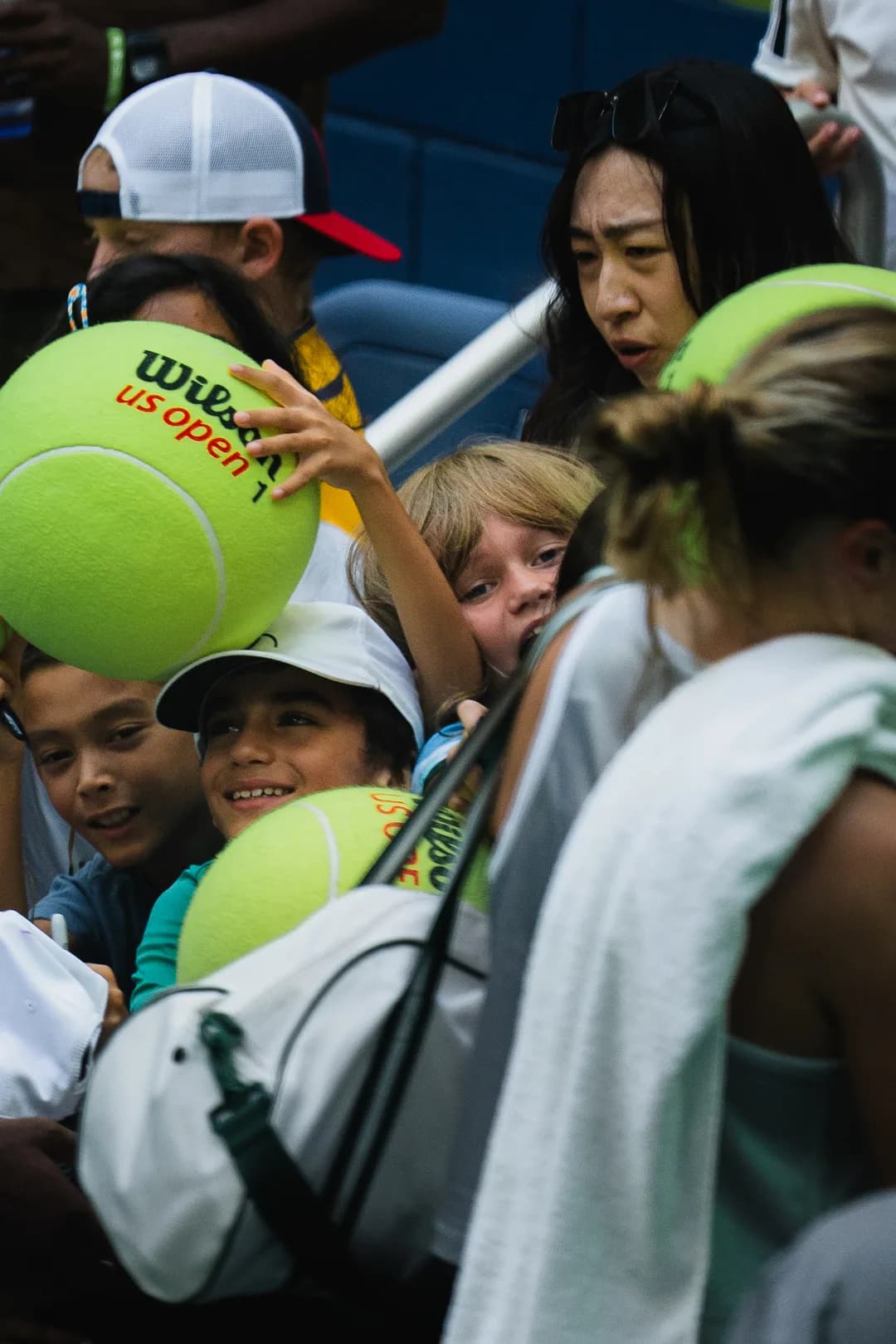 Young fans crowding the rail with oversized US Open balls