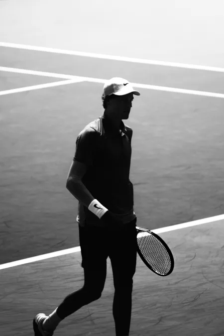 A tennis player crossing the baseline in hard backlight