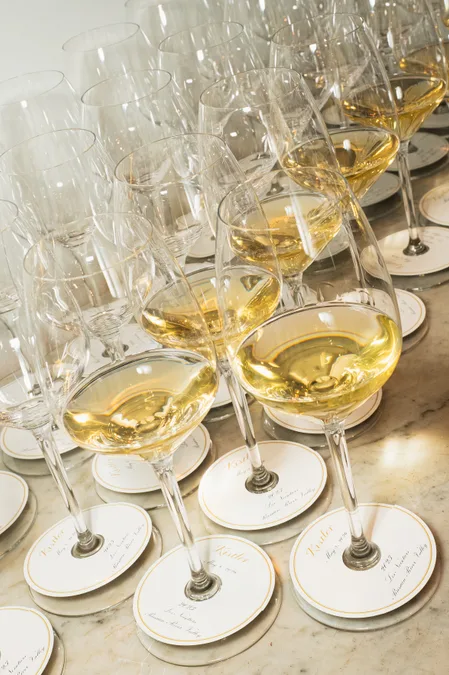 Glasses of white wine lined up on marble at a tasting