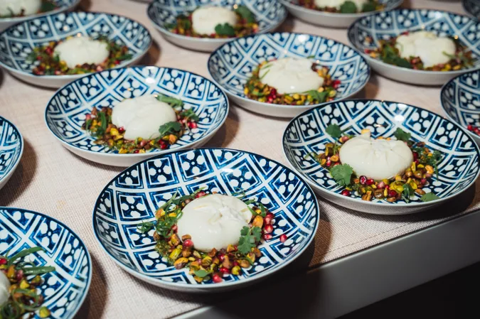 Burrata plated across a run of patterned bowls