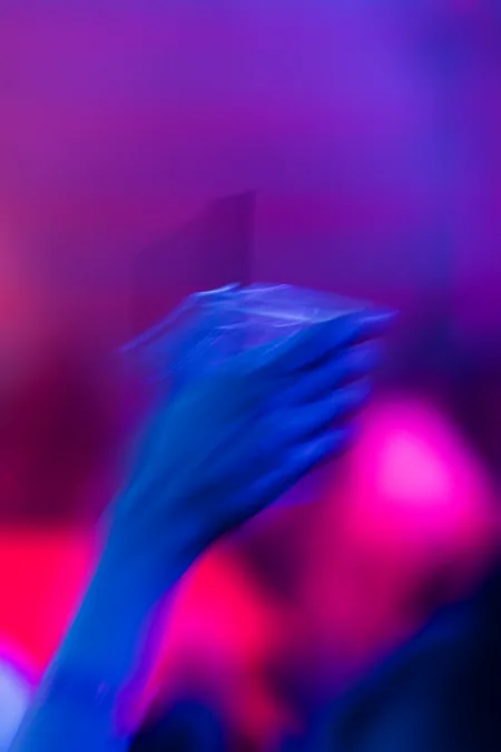 Hand raised in the crowd under pink and blue light