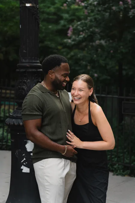 Couple leaning together on a tree-lined city street