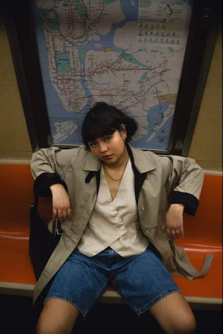A woman sitting back on a subway bench beneath the New York City subway map