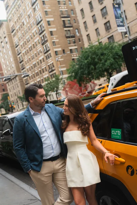 Ned and Alison leaning close against a yellow taxi on a New York City street