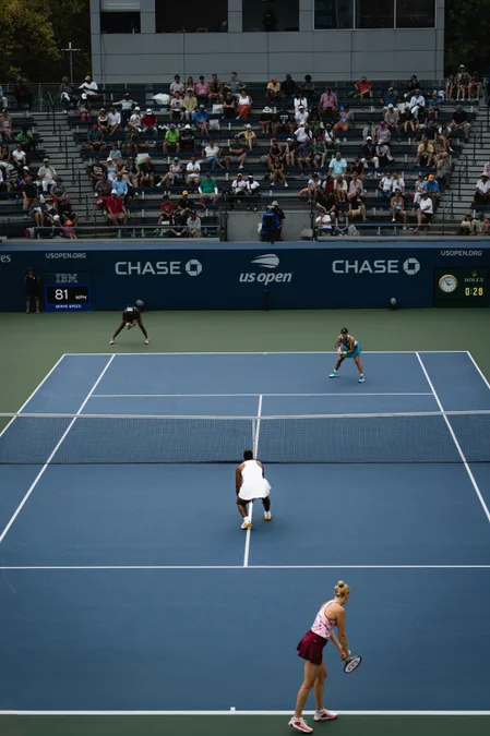 A doubles match on an outer court at the US Open, seen from the stands