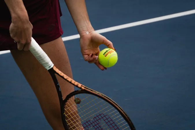 A player cradling the ball beside the racket grip before serving
