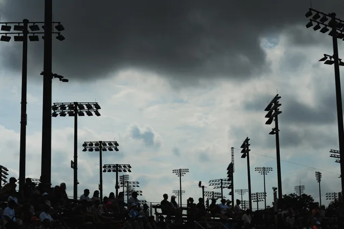 Stadium floodlights silhouetted against gathering storm clouds