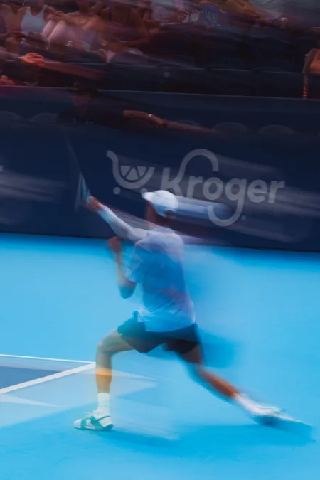 Long lens blur of a forehand under a sponsor board