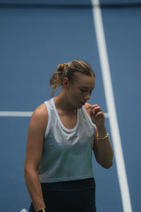 A player looking down between points, hand at her collarbone
