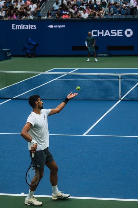 Ball tossed for a serve on Arthur Ashe, opponent waiting across the net