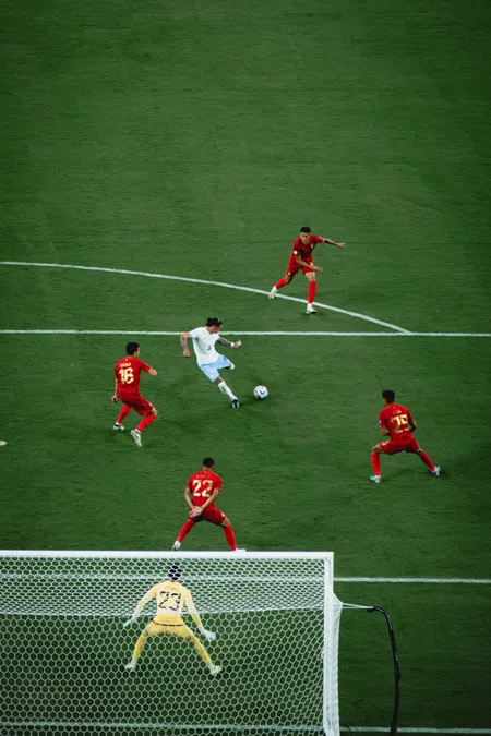 An attacker in white driving at goal through four red defenders